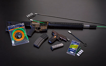 A .22-caliber rifle, magazines, Bore-Whips and Bore-tips arranged on a dark work surface.